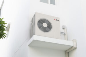 mitsubishi electric heat pump compressor installed on ledge of white house exterior