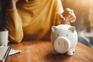 Woman Putting Coin Into Piggy Bank