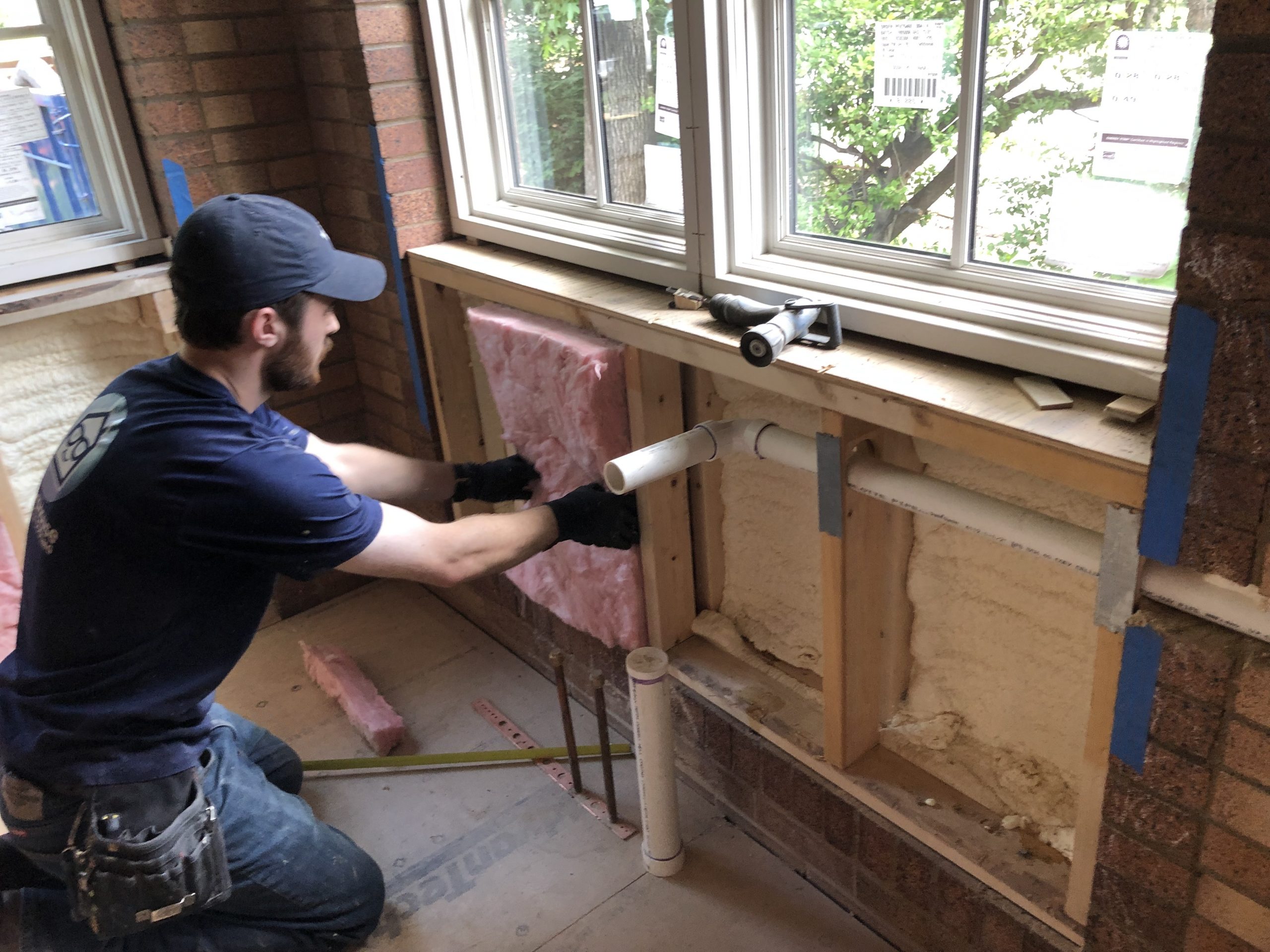 SmartHouse tech installing pink batt insulation in wall under window